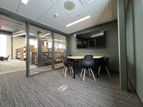 A conference room style table with seating for 4. It also has 1 TV screen and speaker system controlled by an HDMI wall plate. 